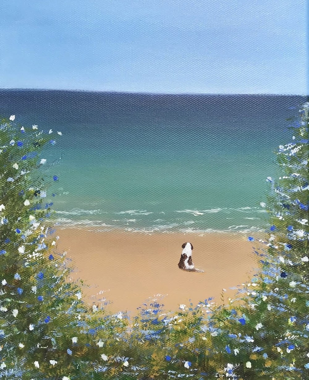 Painting of a small black and white dog sitting on the sand, seen through flowering bushes toward a turquoise sea